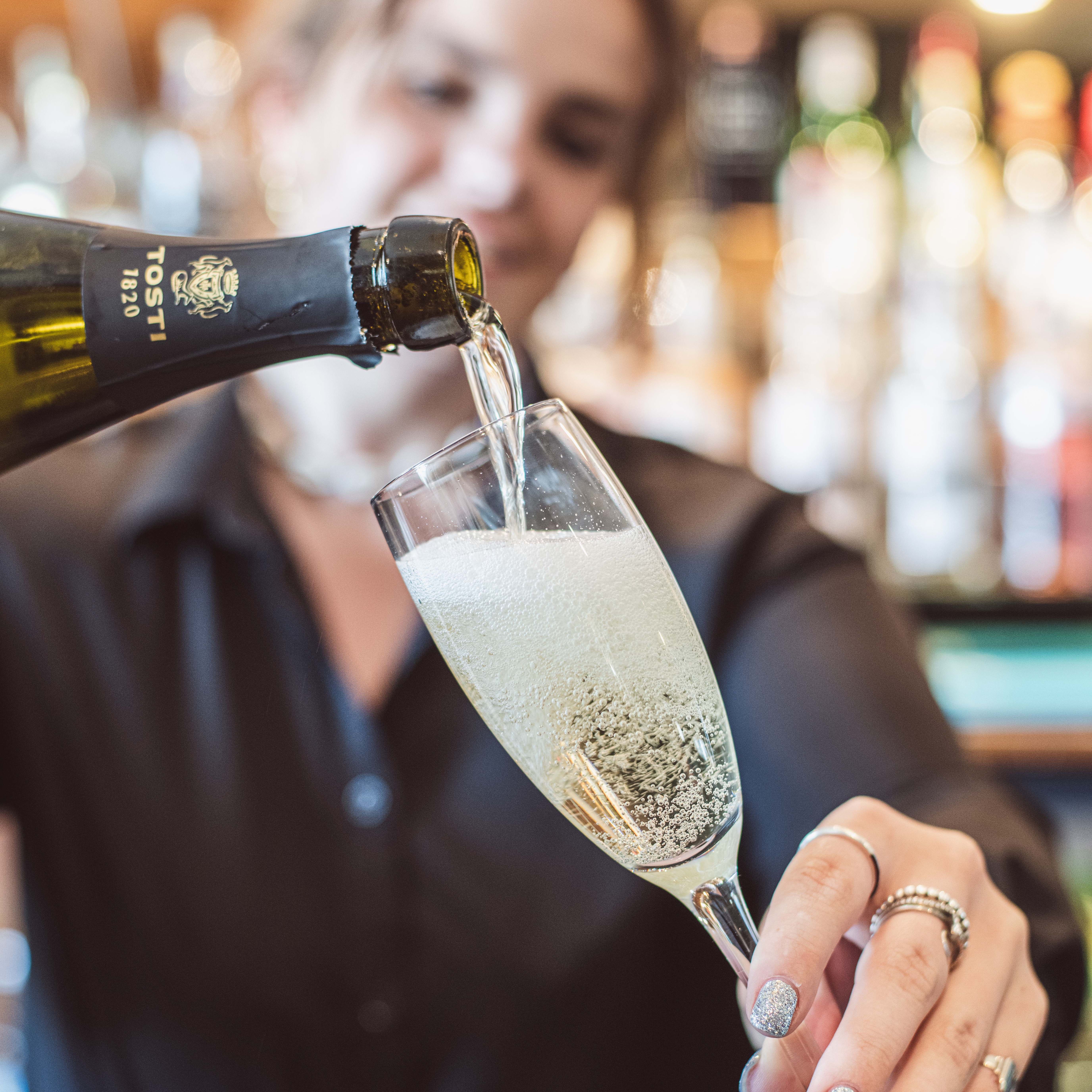 Person pouring sparkling wine into a champagne flute