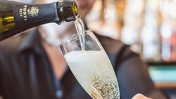 Person pouring sparkling wine into a champagne flute