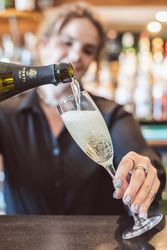 Person pouring sparkling wine into a champagne flute