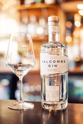 A bottle of Salcombe Gin and a branded wine glass on a bar counter.