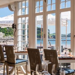 Seaside restaurant with tables near large windows overlooking a beach and ocean view