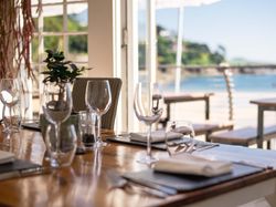 Table set for dining at a restaurant with a view of the beach outside.