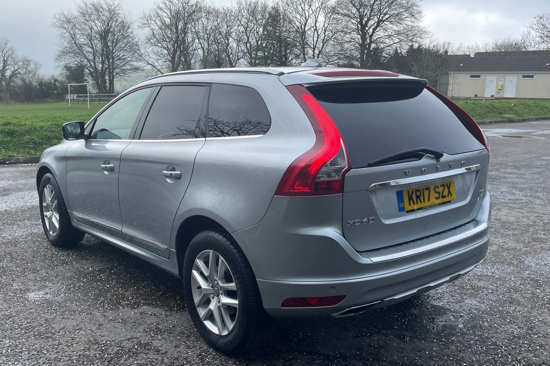 Silver Volvo XC60 SUV parked in an outdoor lot on a cloudy day
