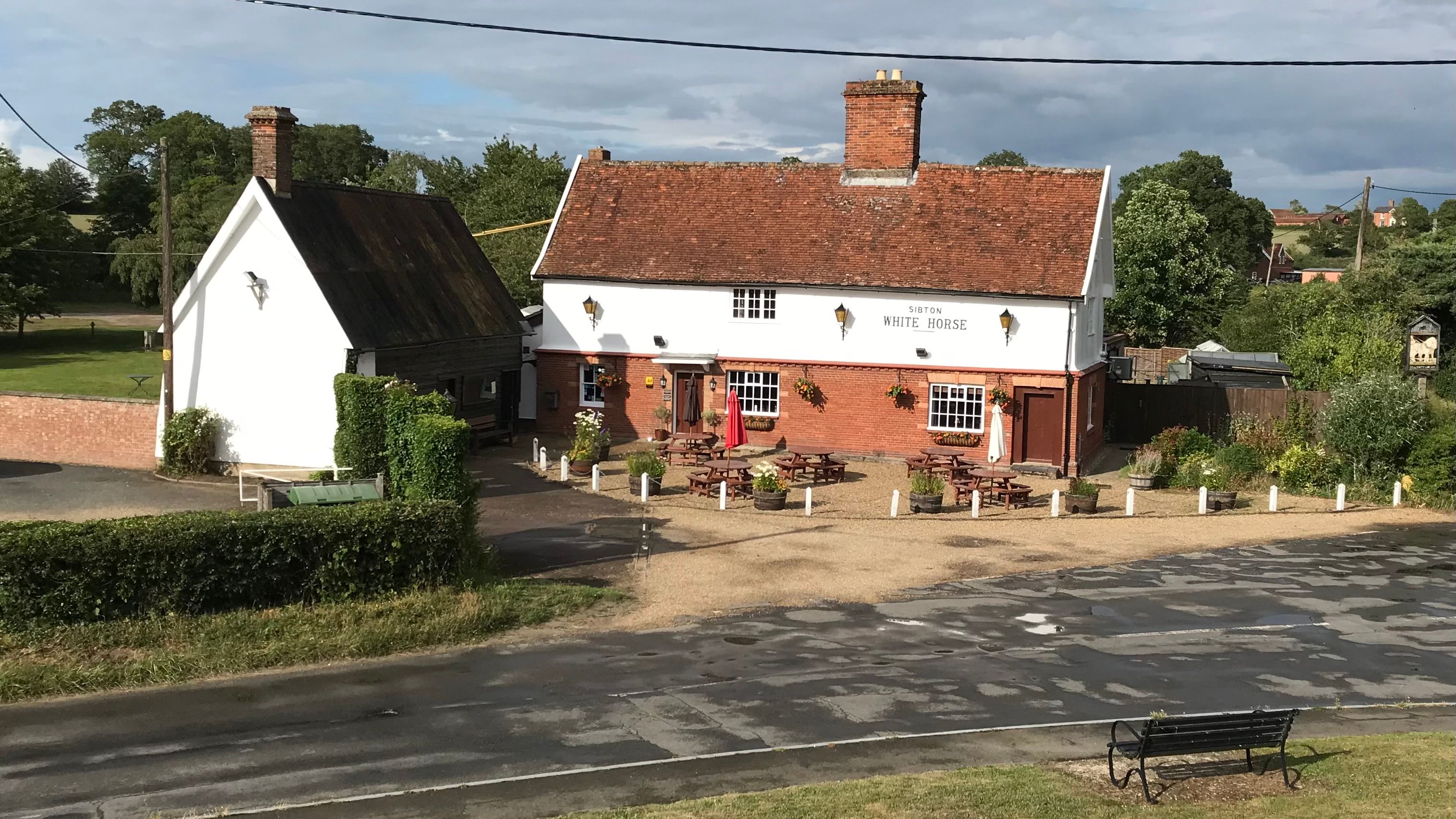 A traditional English pub called 'Sibton White Horse' with outdoor seating and a red-tiled roof.