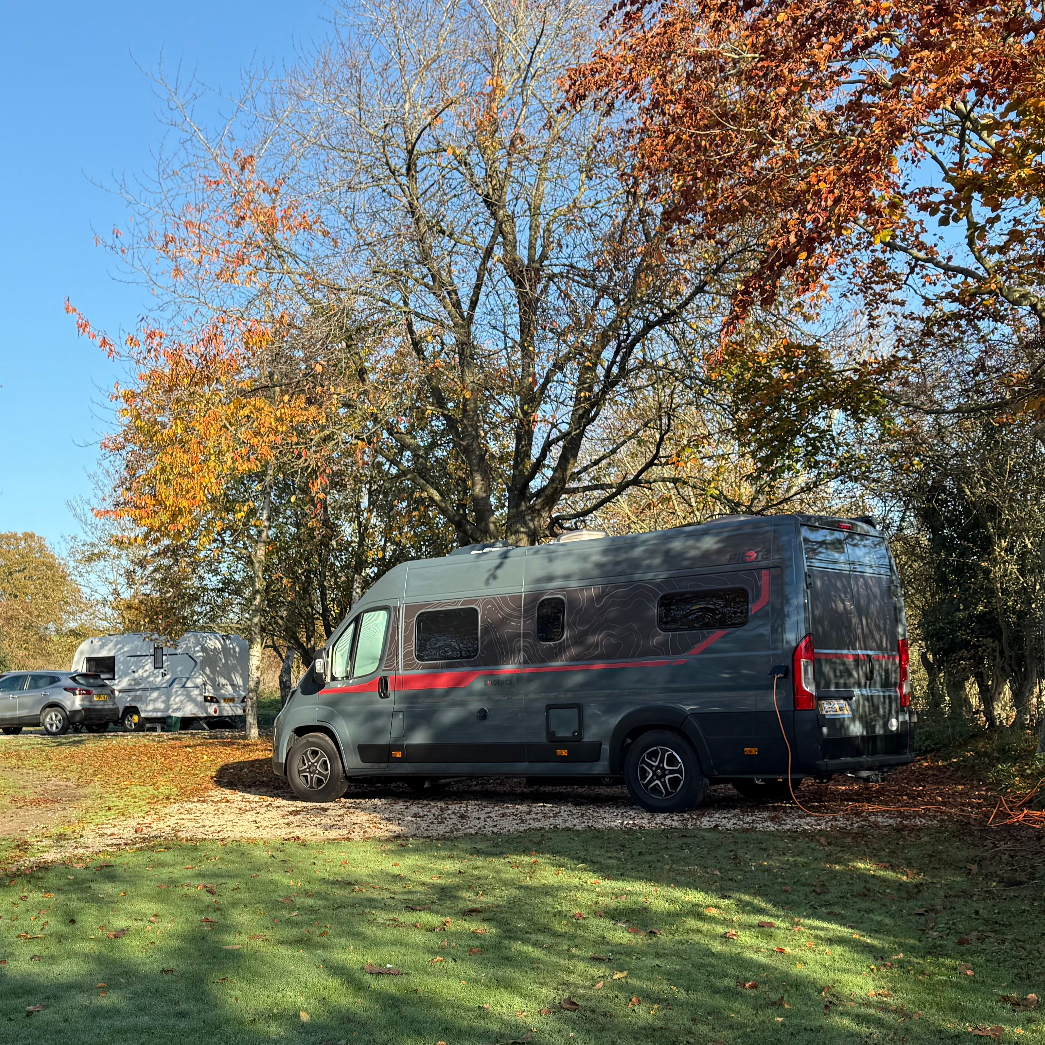 Campervans parked under autumn trees in a scenic outdoor setting