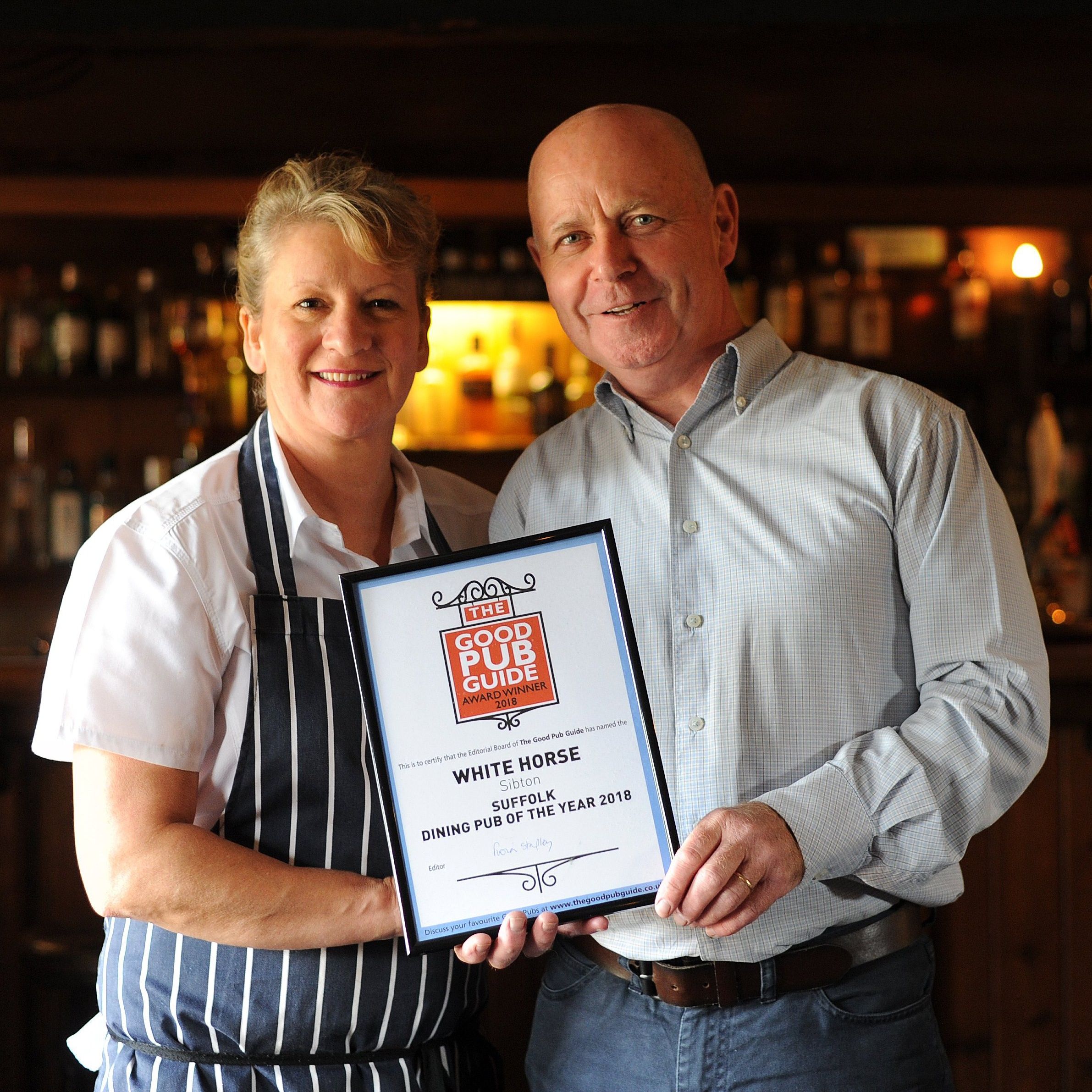 Two people holding a framed award for Dining Pub of the Year 2018 from The Good Pub Guide.