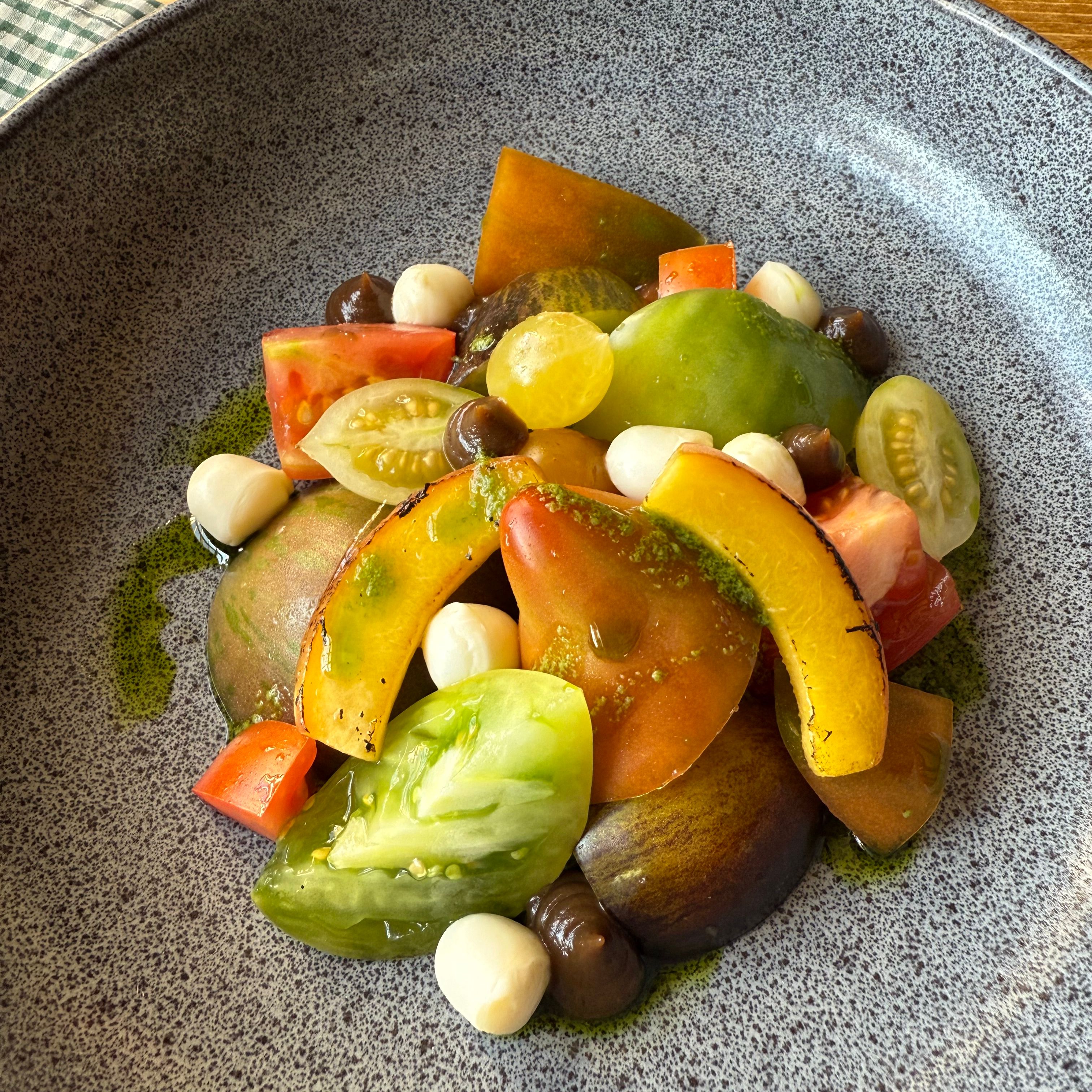 Colorful tomato salad with mozzarella balls and olives in a gray ceramic bowl