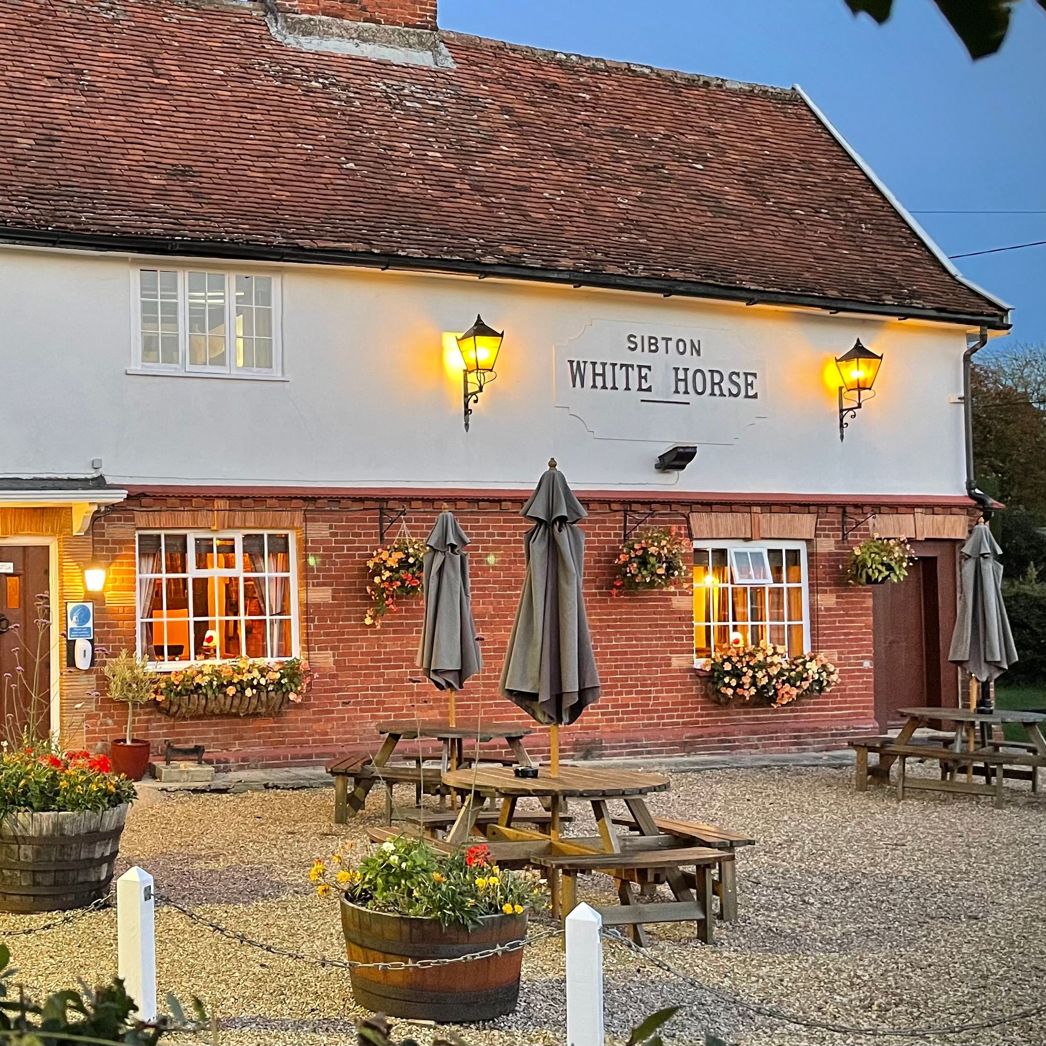 Sibton White Horse pub exterior at dusk with outdoor seating and flowers