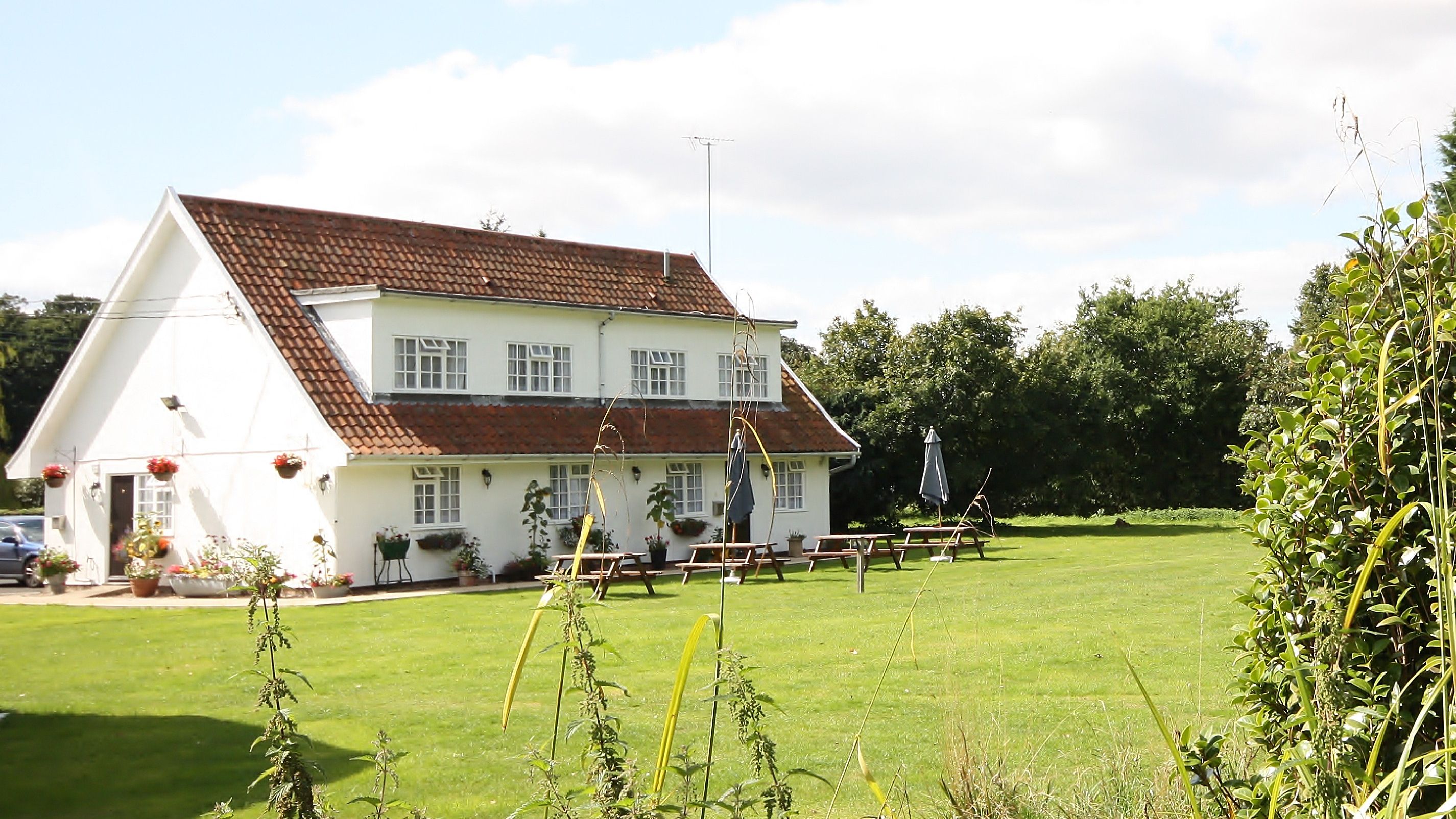White two-story house with red tiled roof and large grassy yard