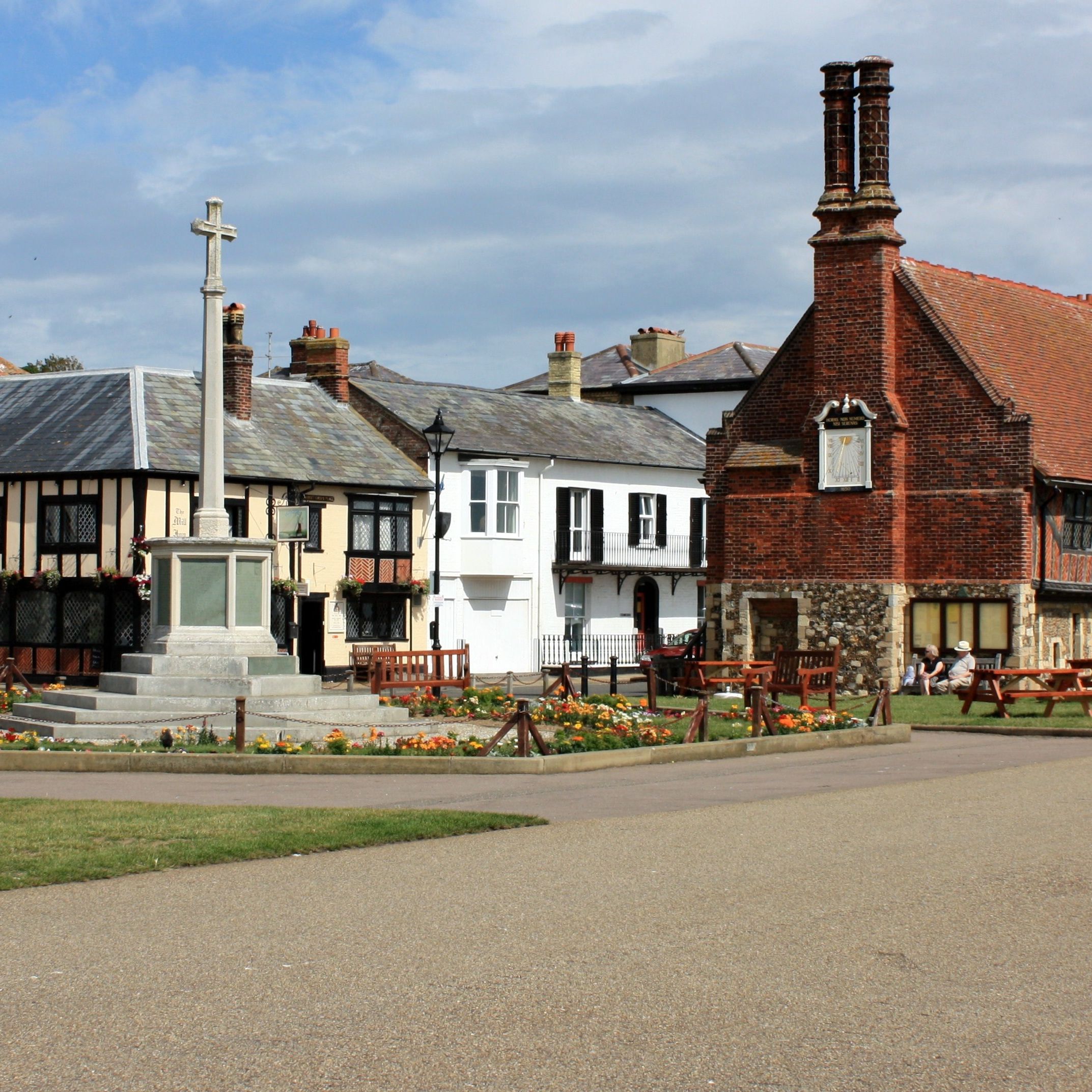 Historic village square with stone war memorial and old timber-framed buildings