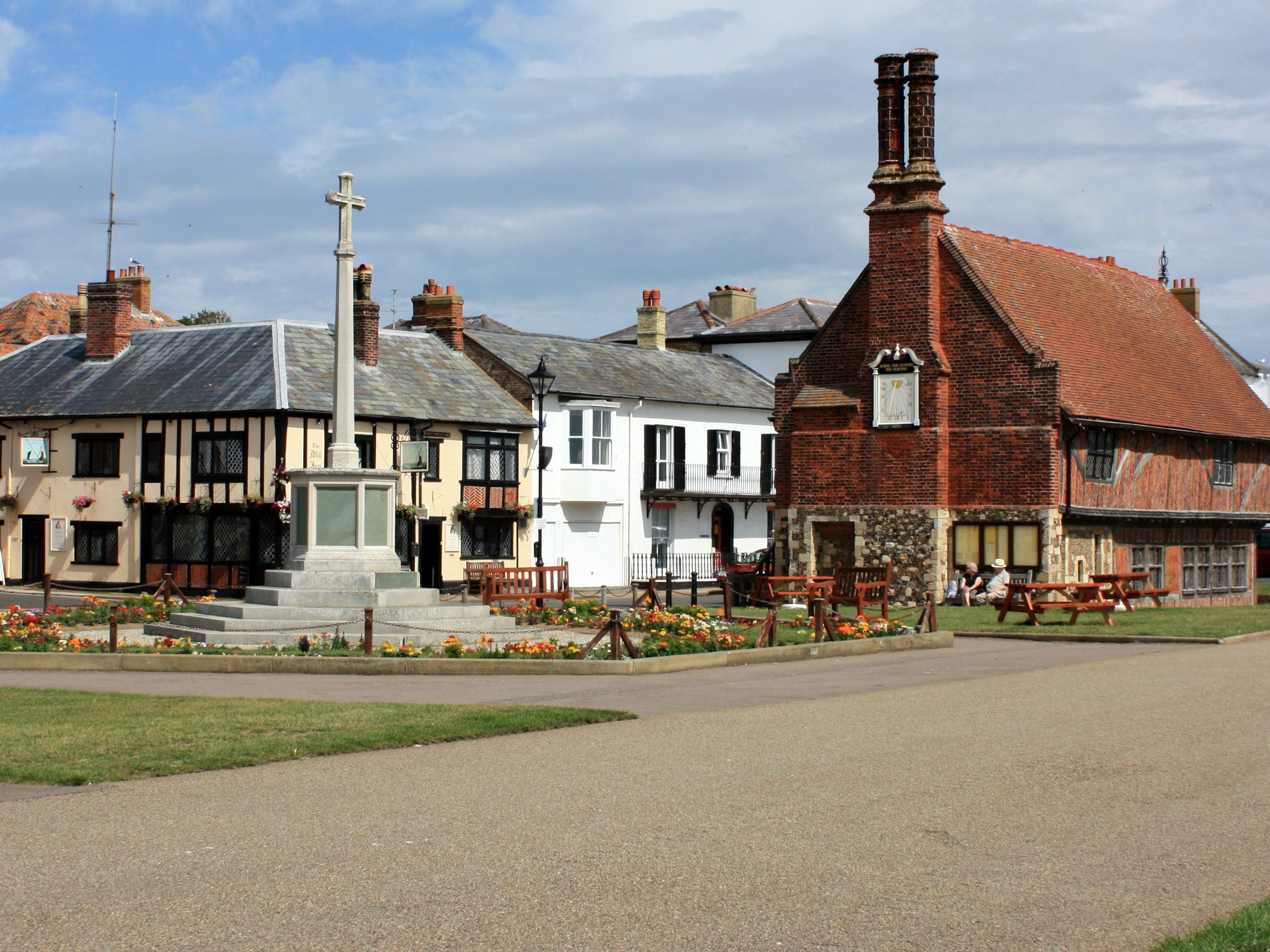 Historic village square with stone war memorial and old timber-framed buildings
