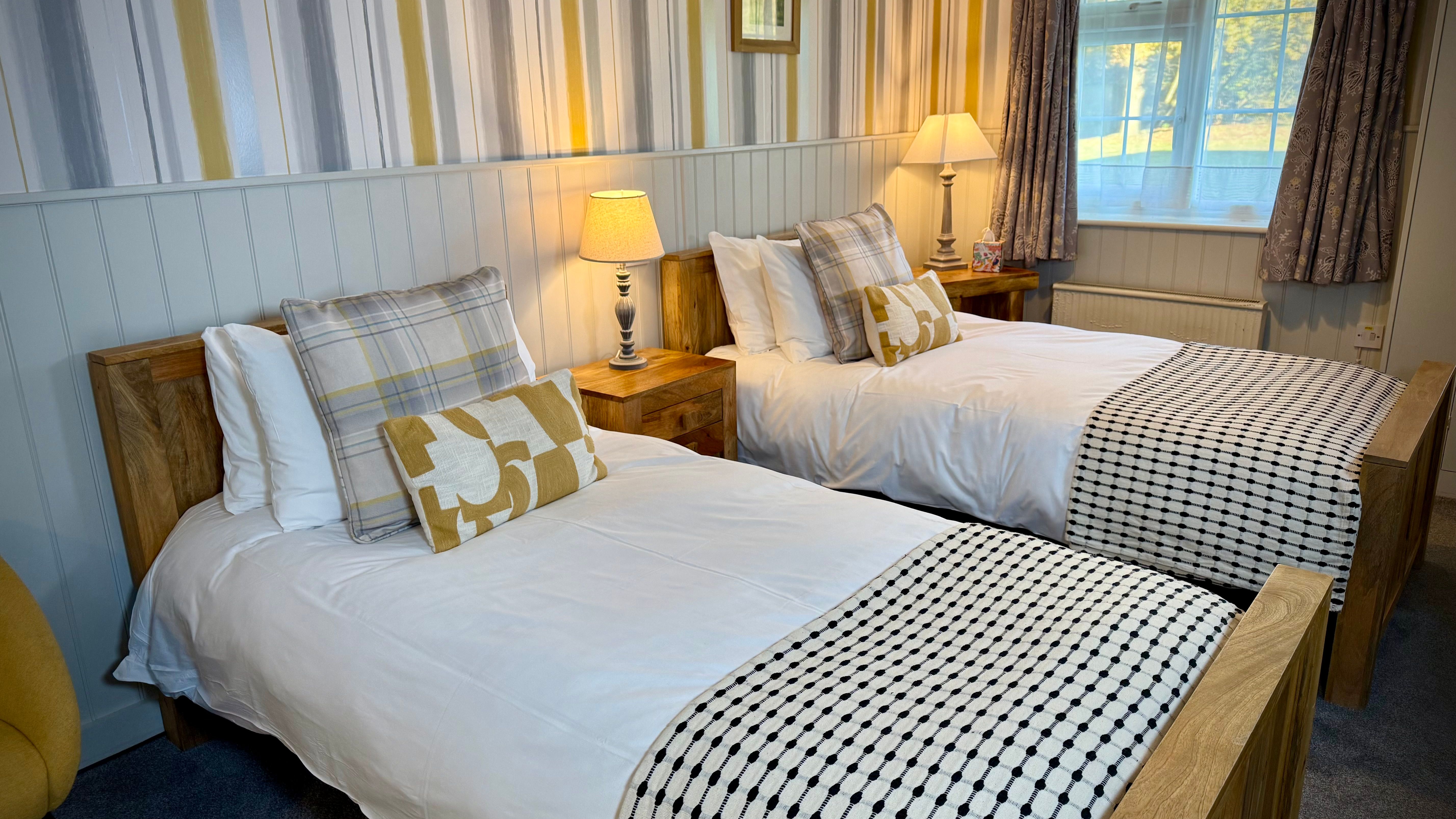 Cozy twin bedroom with wooden beds, white bedding, and warm lighting