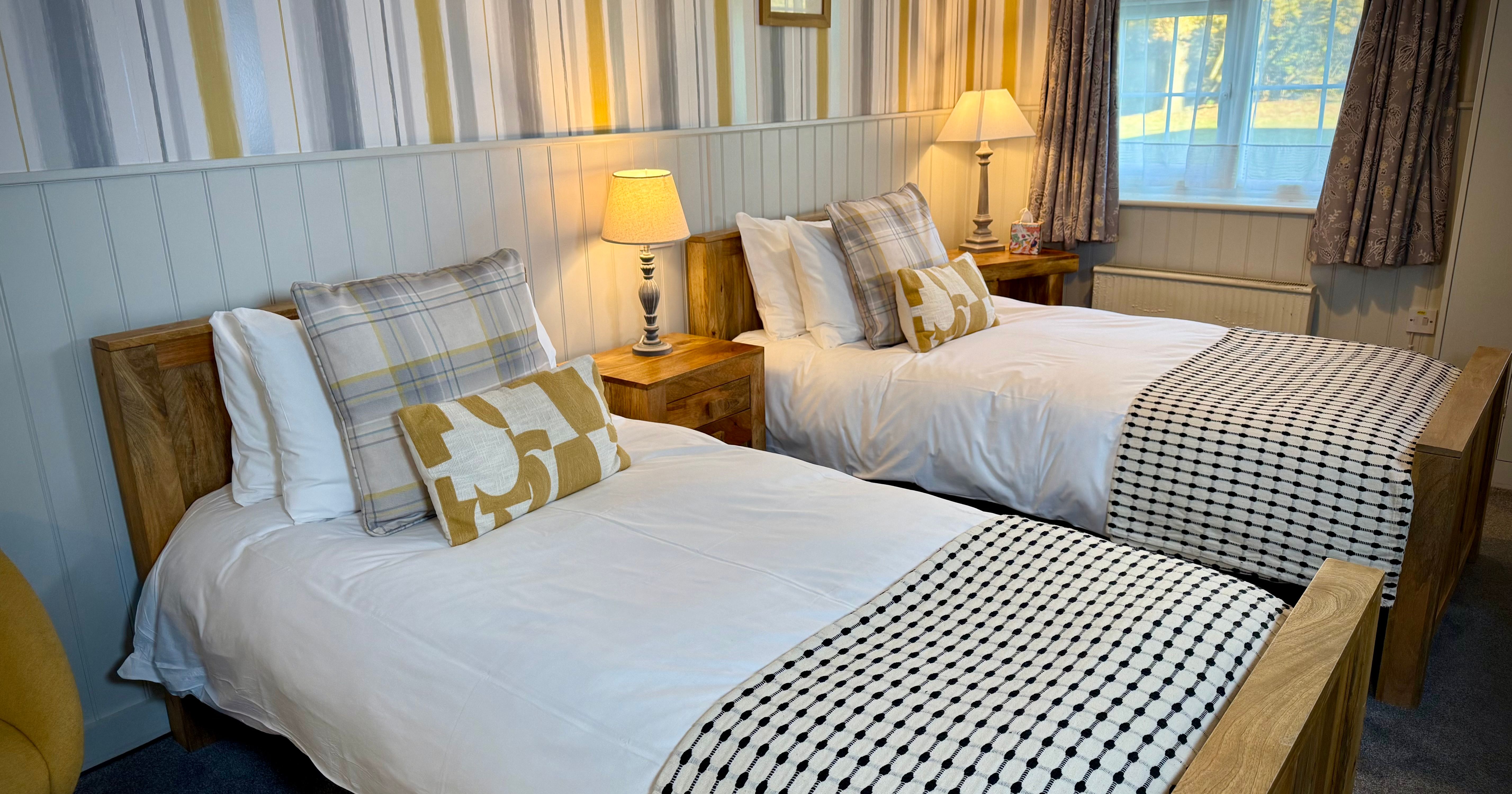 Cozy twin bedroom with wooden beds, white bedding, and warm lighting