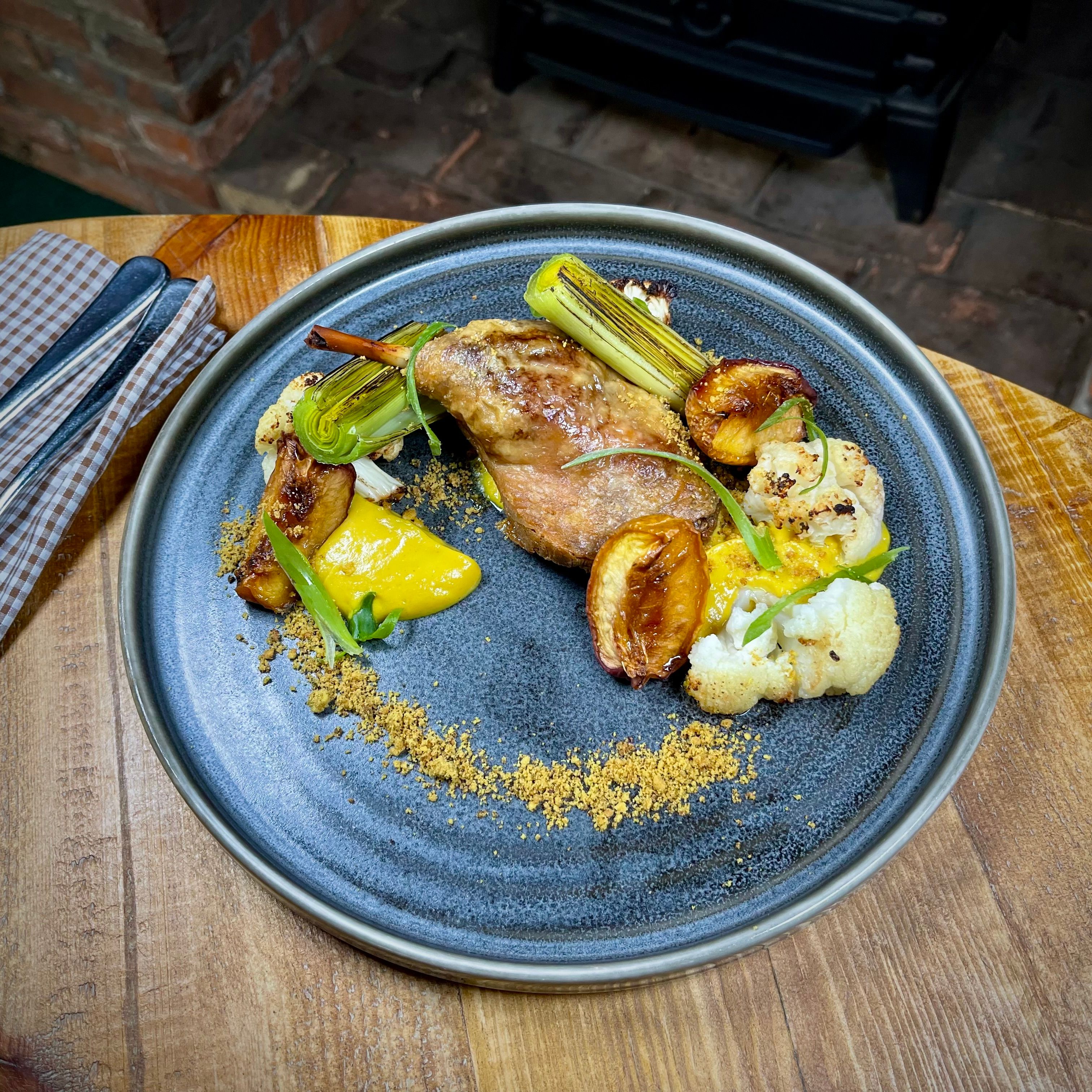 Plated gourmet dish featuring roasted poultry, vegetables, and garnishes