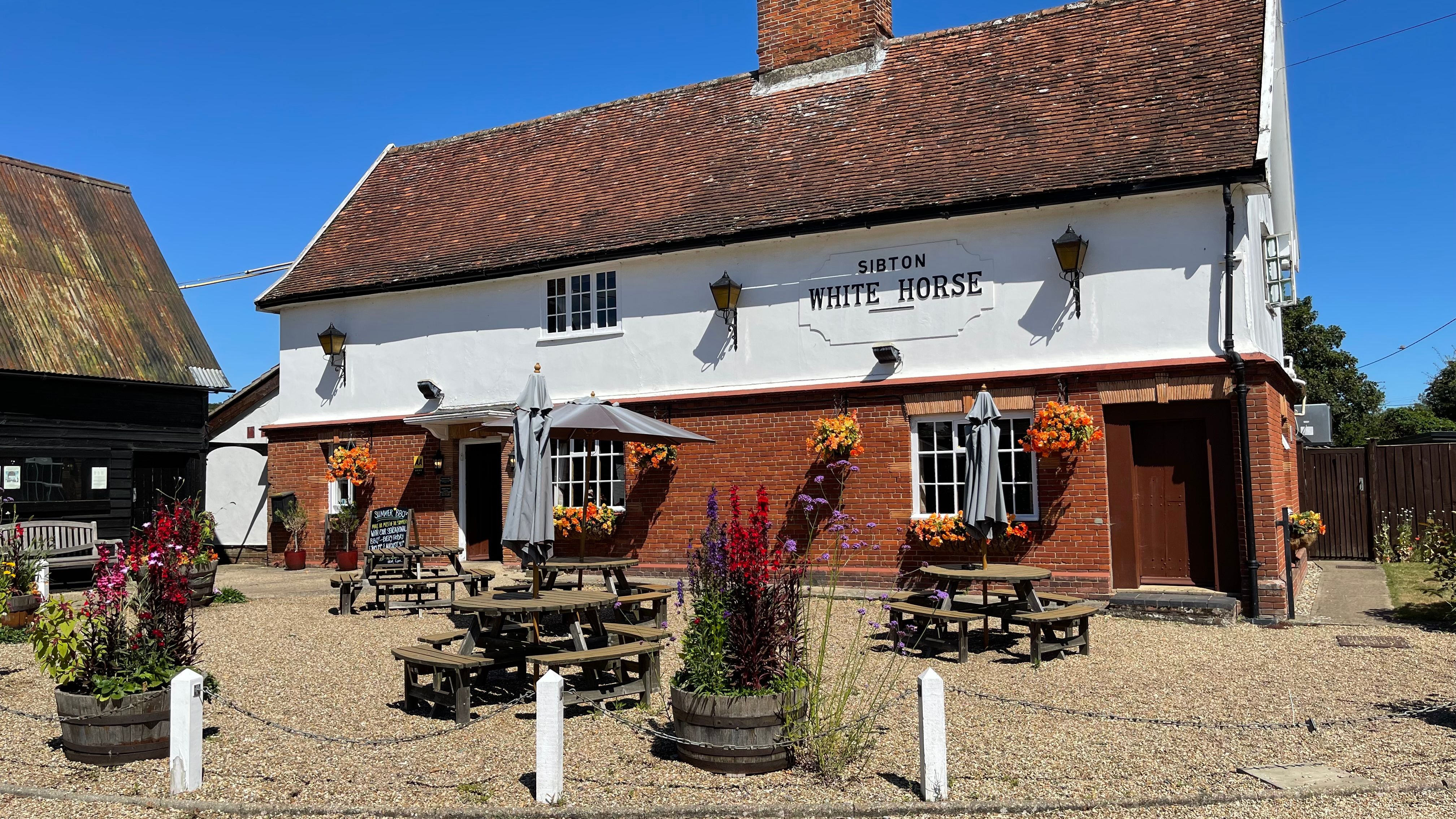 Traditional English pub with outdoor seating and flower baskets, named Sibton White Horse.