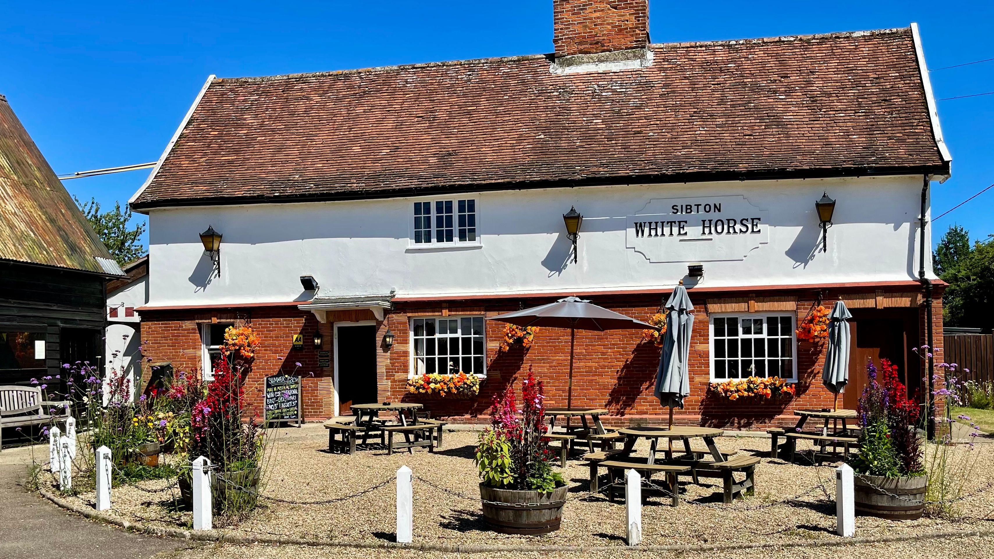 Front view of Sibton White Horse pub with outdoor seating and flower planters