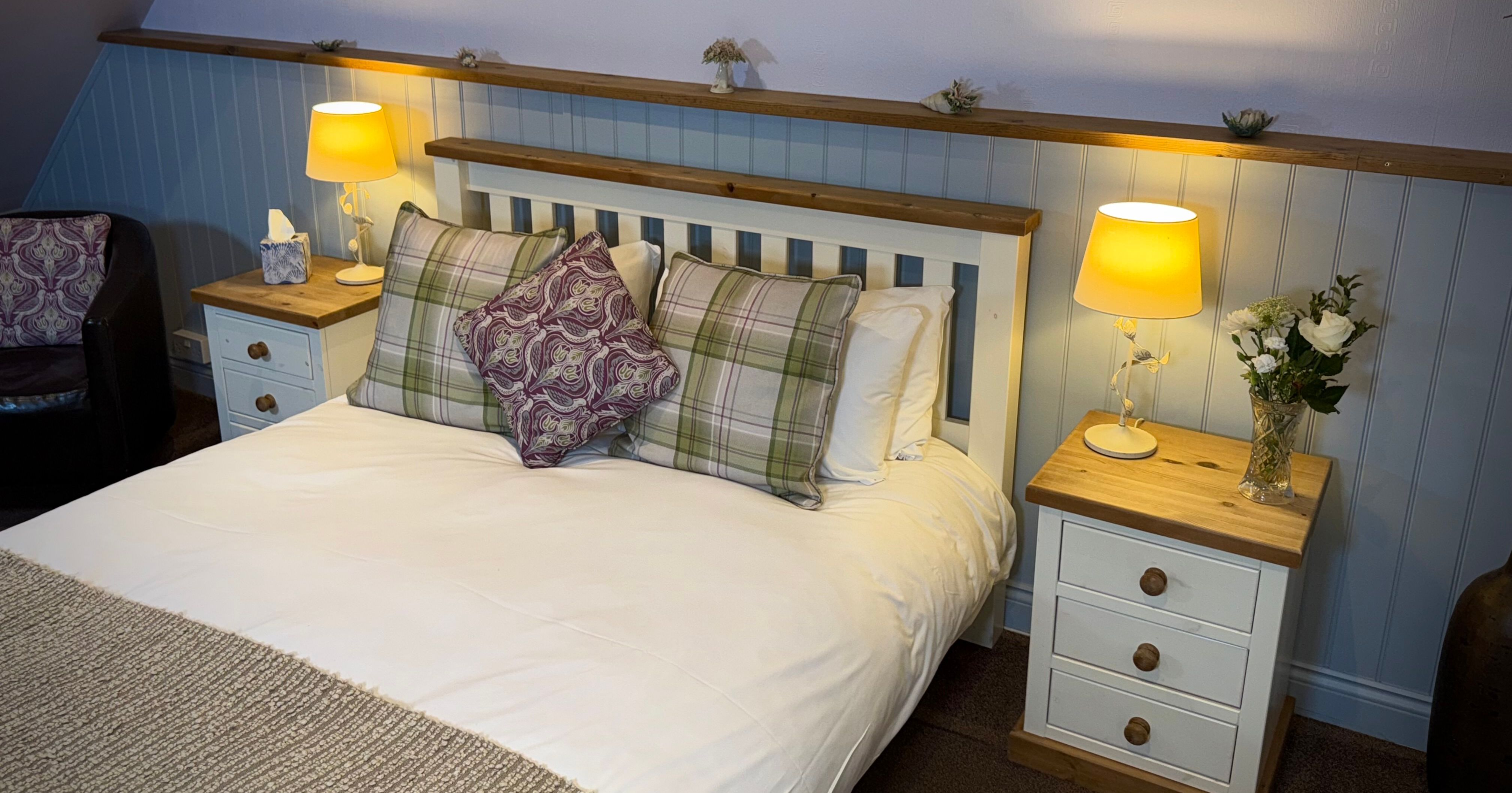 Cozy bedroom with a double bed, bedside tables, lamps, and decorative pillows.