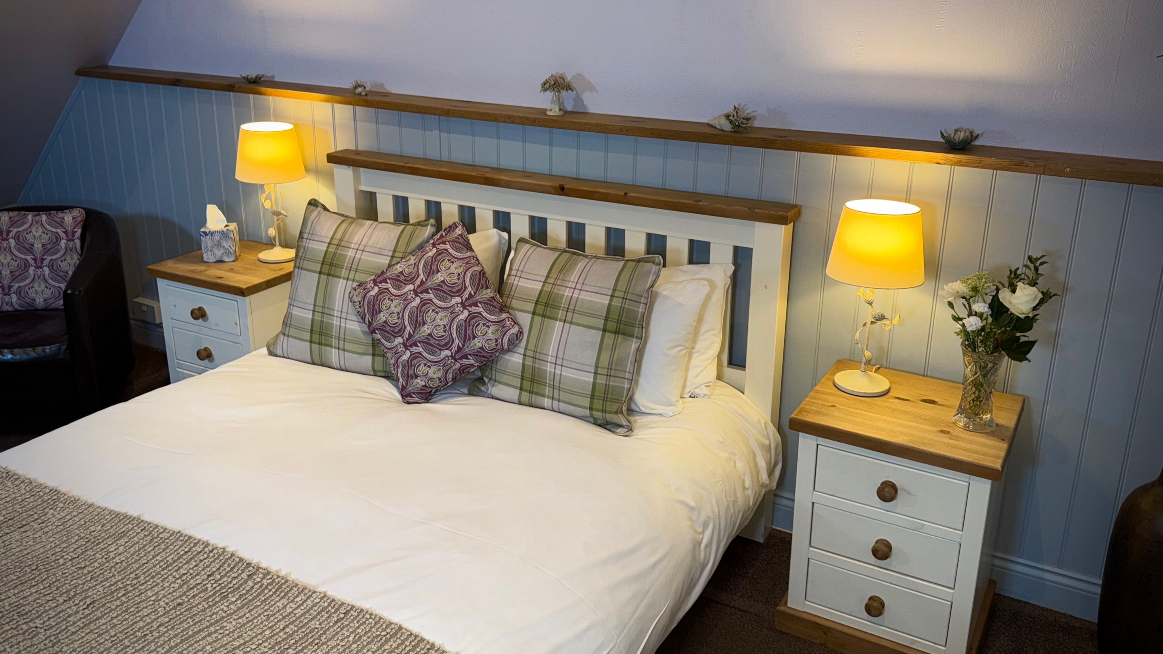 Cozy bedroom with a double bed, bedside tables, lamps, and decorative pillows.