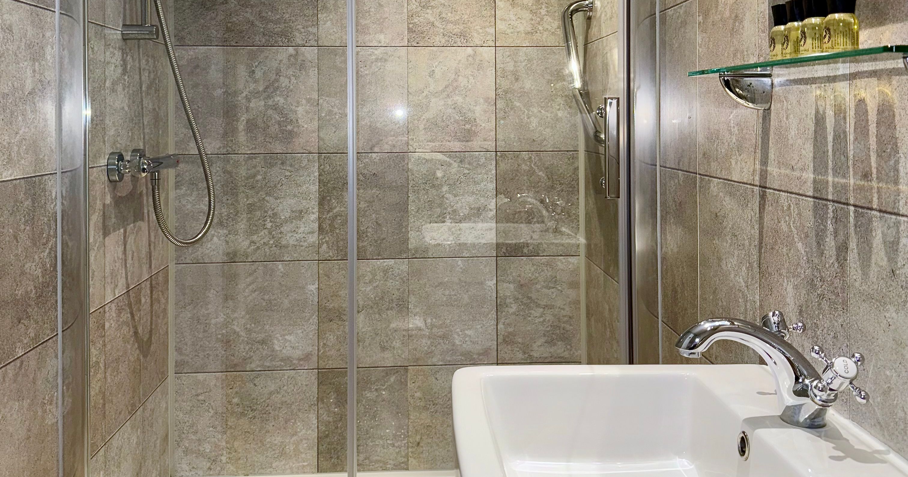 Modern bathroom with a glass shower enclosure, tiled walls, and a white sink.