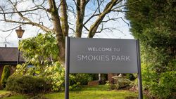 A large sign that reads 'Welcome to Smokies Park' standing on a grassy area surrounded by trees and bushes.