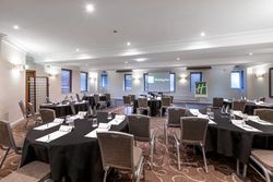 Conference room setup with round tables, chairs, and Holiday Inn branding.