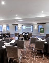 Conference room setup with round tables, chairs, and Holiday Inn branding.