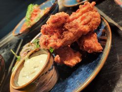 A plate of crispy fried chicken tenders served with a side of creamy dipping sauce.