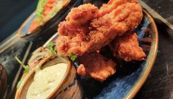 A plate of crispy fried chicken tenders served with a side of creamy dipping sauce.