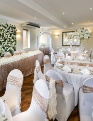 Elegant wedding reception hall with white and gold decor, floral arrangements, and banquet tables.