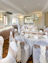 Elegant wedding reception hall with white and gold decor, floral arrangements, and banquet tables.