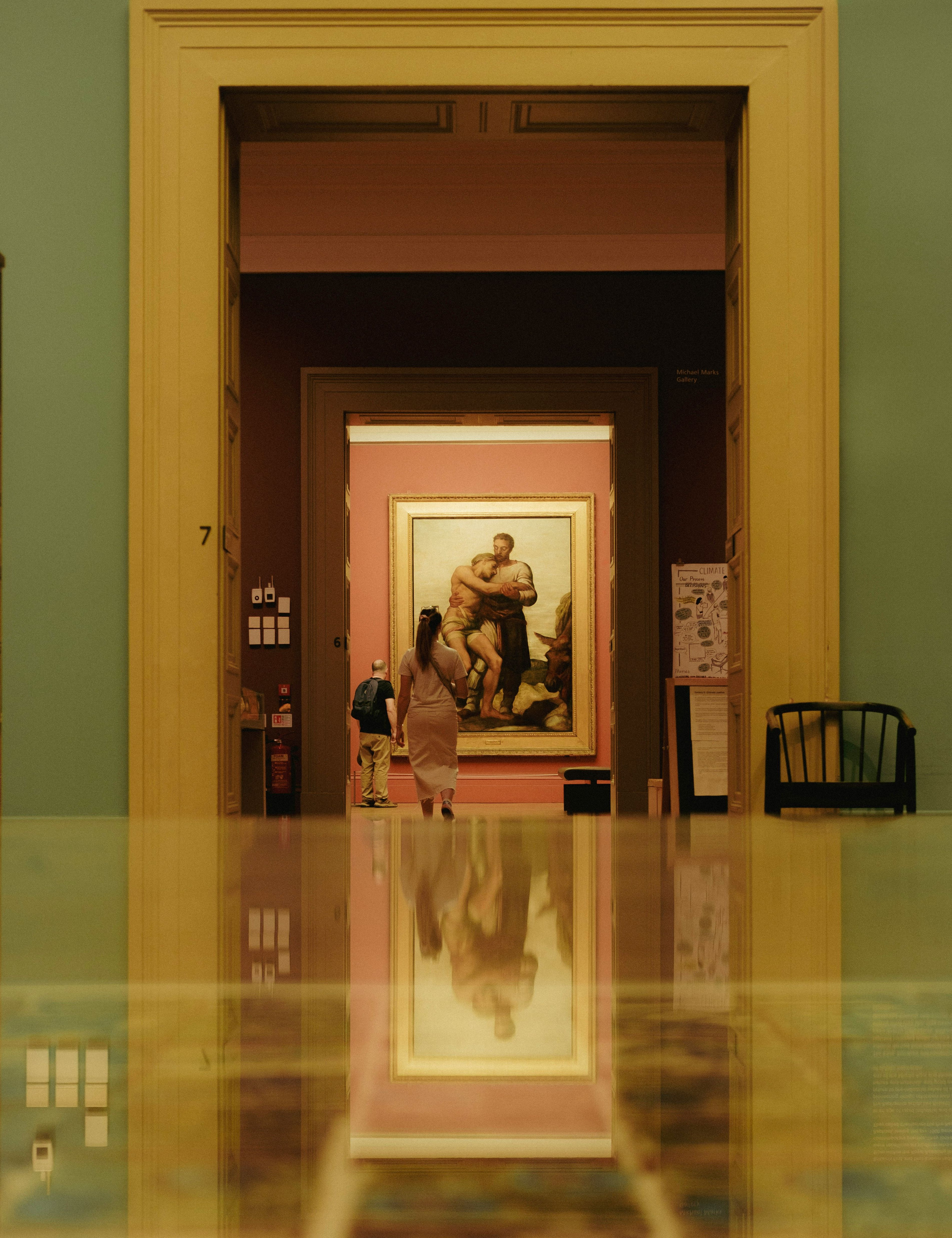 People observing classic painting in an art museum with polished floor reflecting the artwork