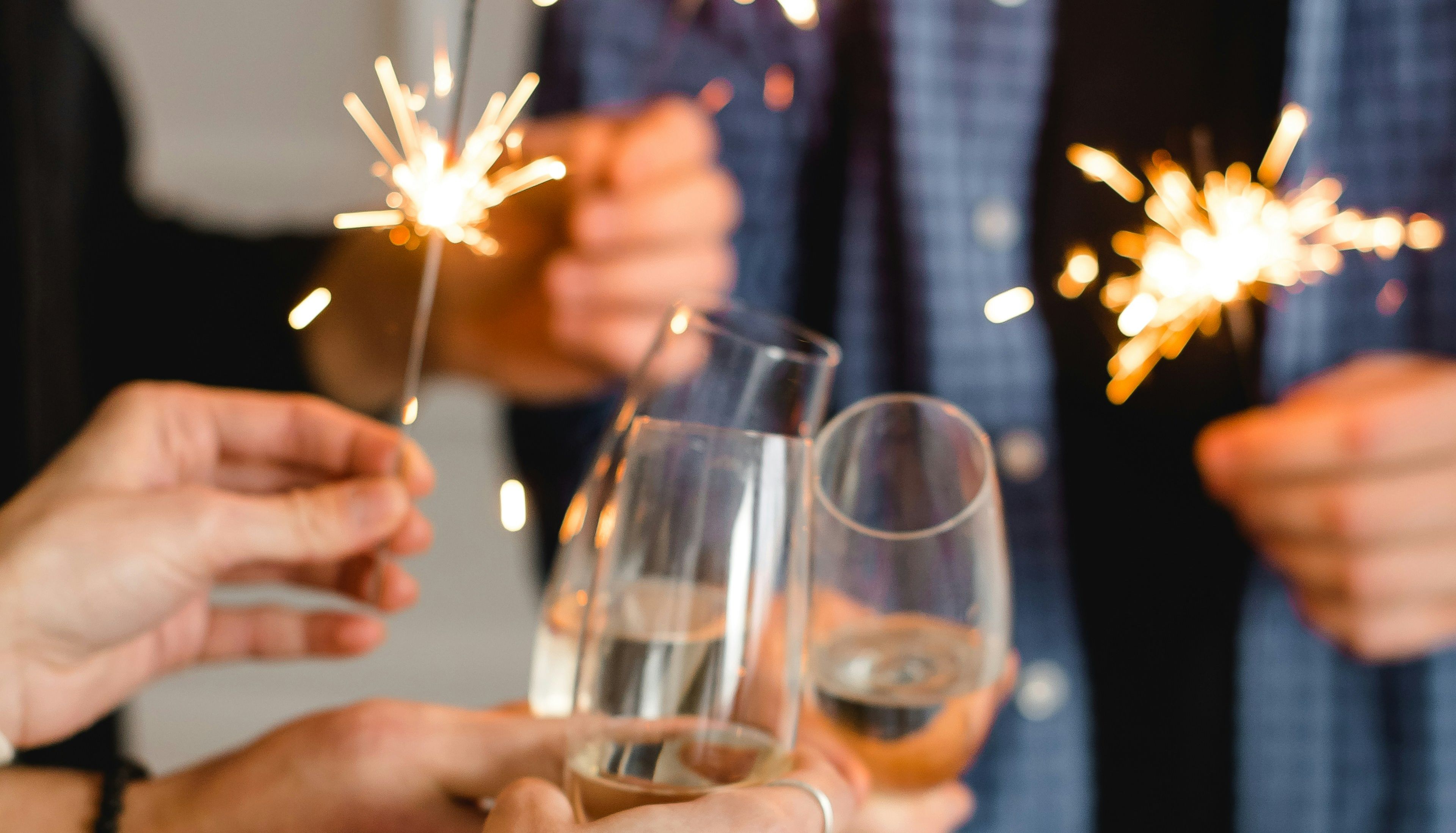People holding sparklers and clinking glasses of champagne at a celebration.