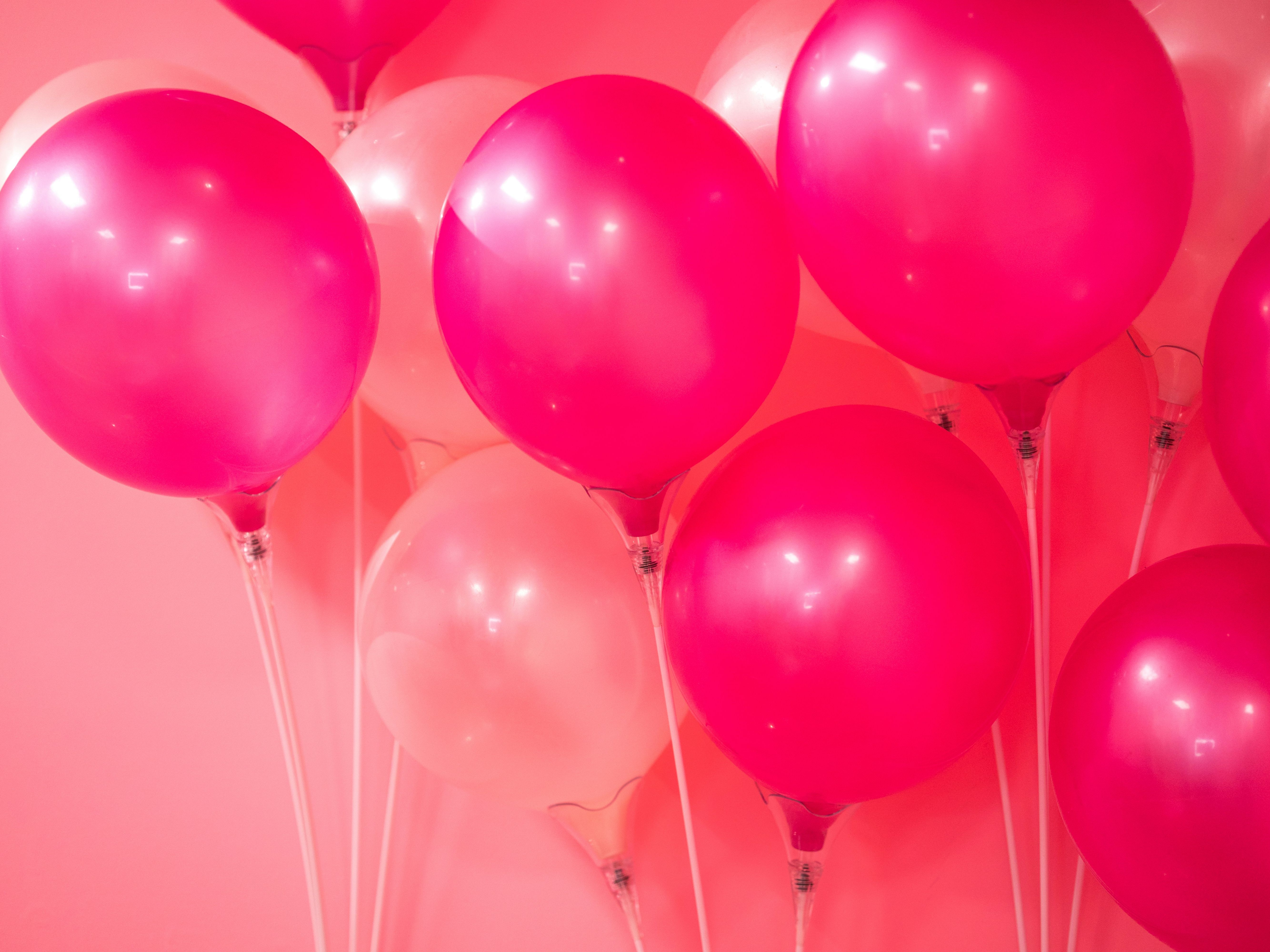 A bunch of pink and light pink balloons against a pink background.