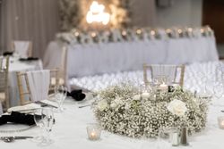 Elegant wedding reception table setting with white flowers, glass candle holders, and soft lighting in a romantic decor.