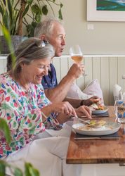 Smiling couple enjoying a meal with wine at a cozy restaurant table.