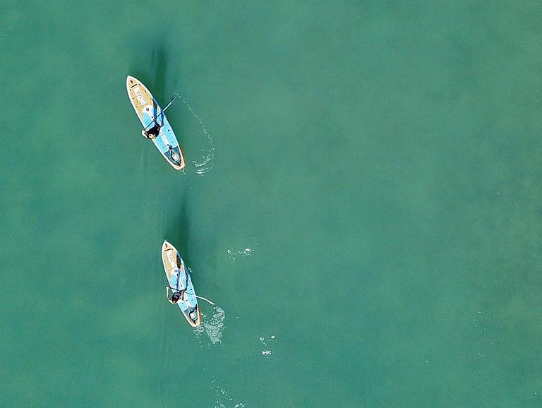 Aerial view of two people paddleboarding on calm turquoise sea