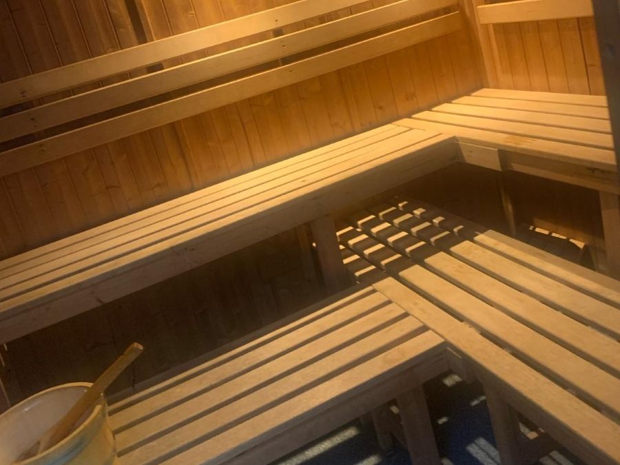 Interior of a wooden sauna with benches and a wooden bucket with a ladle.