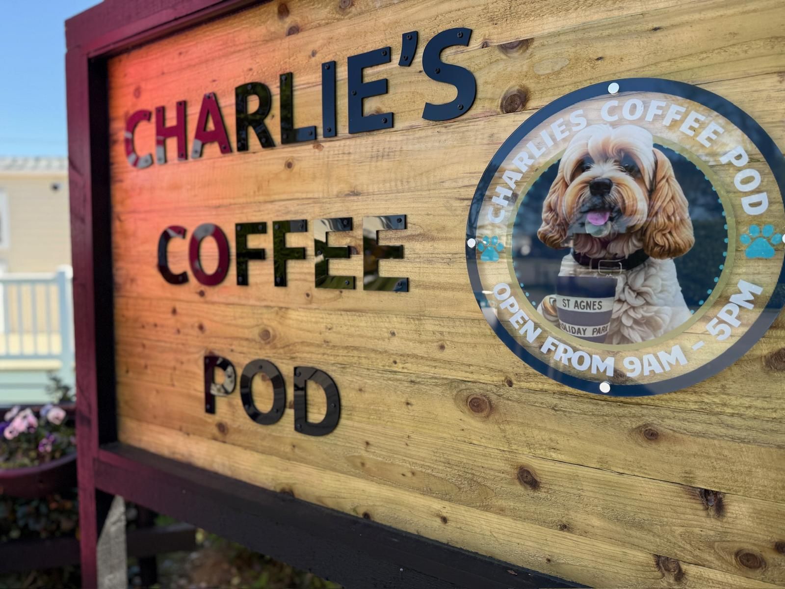 Charlie's Coffee Pod wooden sign with a circular picture of a dog and operating hours.