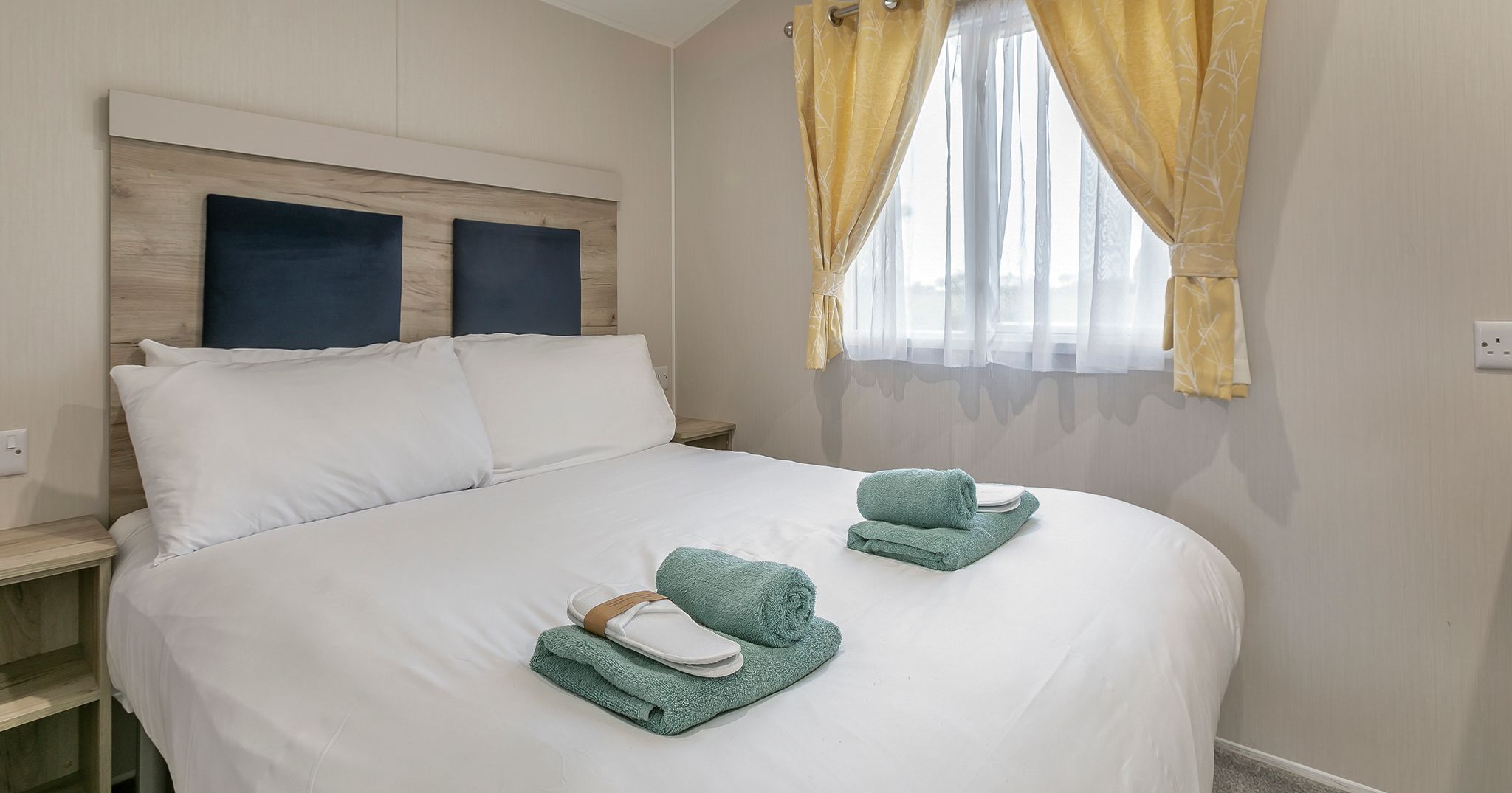 Modern bedroom with a large bed, white linens, and neatly folded towels on top
