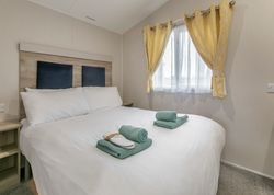 Modern bedroom with a large bed, white linens, and neatly folded towels on top