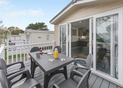 Outdoor dining area on the deck of a modern mobile home patio with table and chairs
