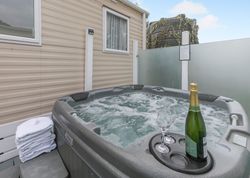 Outdoor hot tub with bubbling water, champagne bottle, and two glasses beside a stack of towels