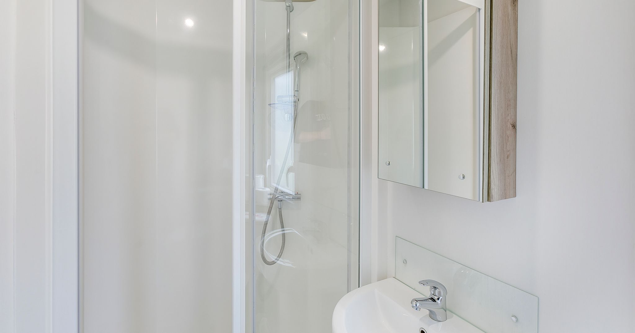 Modern compact bathroom with glass shower and white sink