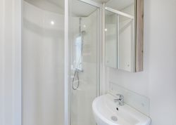 Modern compact bathroom with glass shower and white sink
