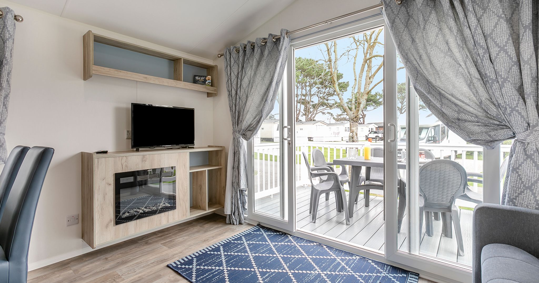 Modern living room with large sliding glass doors opening to a deck with outdoor seating
