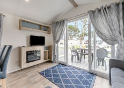 Modern living room with large sliding glass doors opening to a deck with outdoor seating