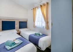 Twin bedroom with two single beds, blue accents, and a window with yellow curtains