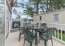 Outdoor deck with plastic table and chairs next to a mobile home