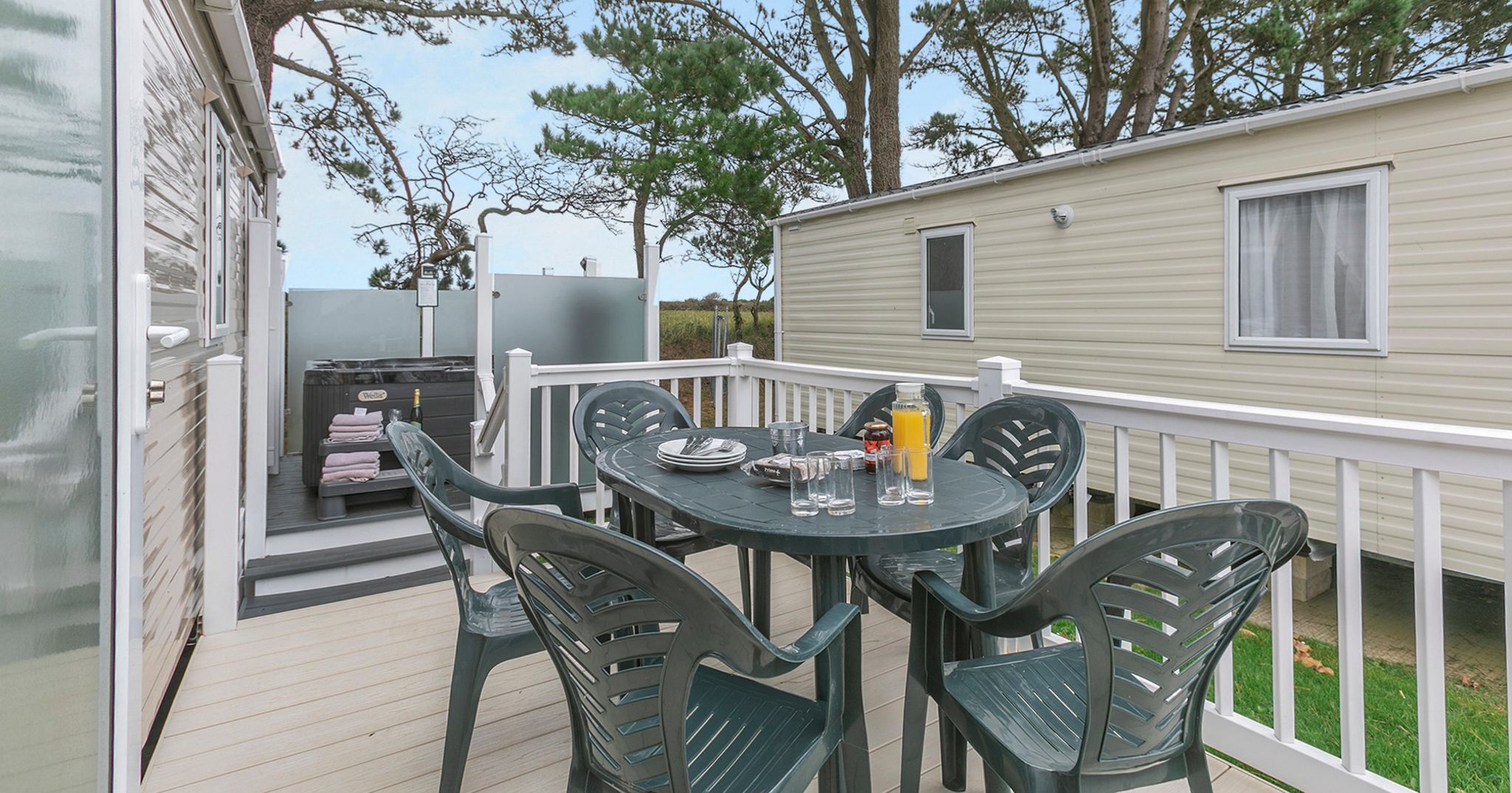 Outdoor deck with plastic table and chairs next to a mobile home