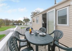Outdoor table with chairs and breakfast items on the deck of a mobile home.